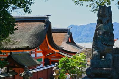 Itsukushima Shrine Buildings with Guardian Statue and Mountains